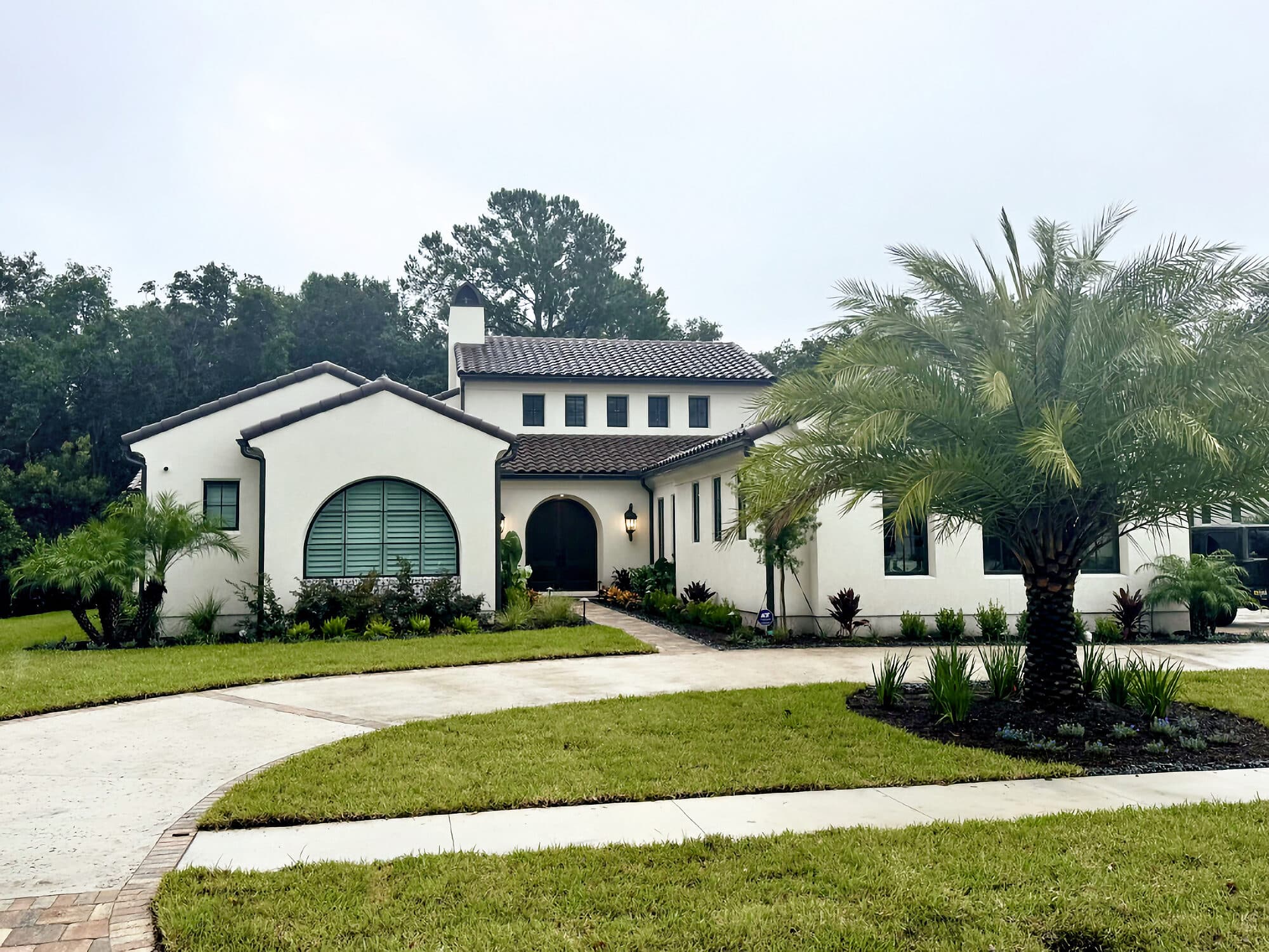 White Spanish-style custom home with a barrel-tile roof and arched entry, built by Integrity Construction Co. in Nocatee, Florida