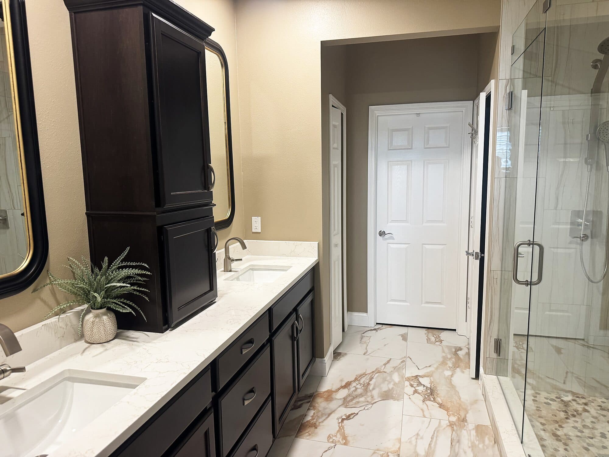 Renovated marble bathroom with a dark vanity after Integrity Construction Co.'s remodel in Jacksonville, Florida