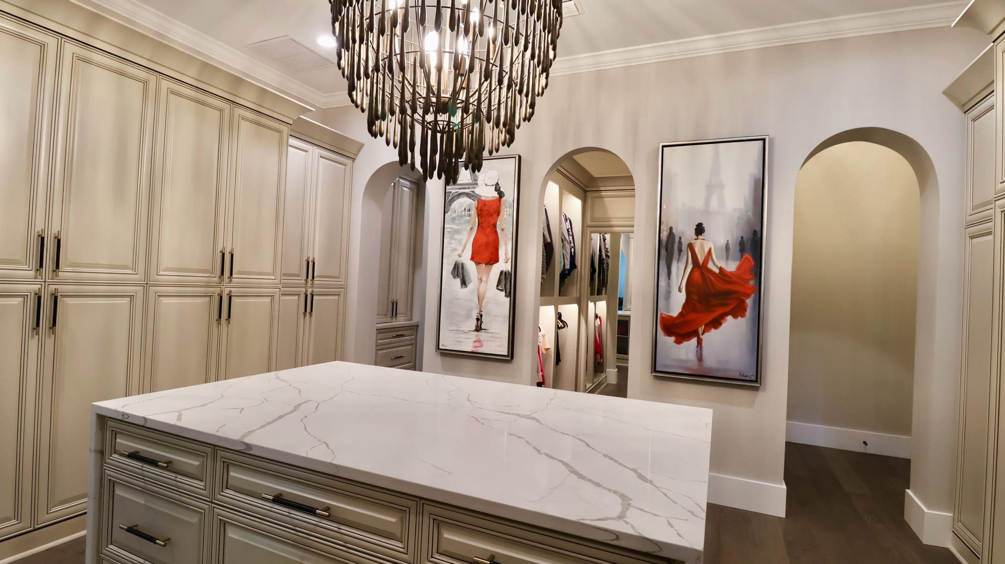 Custom dressing room with a book-matched marble island, glazed furniture-style cabinetry, and a beaded chandelier in a custom home in Nocatee, Florida